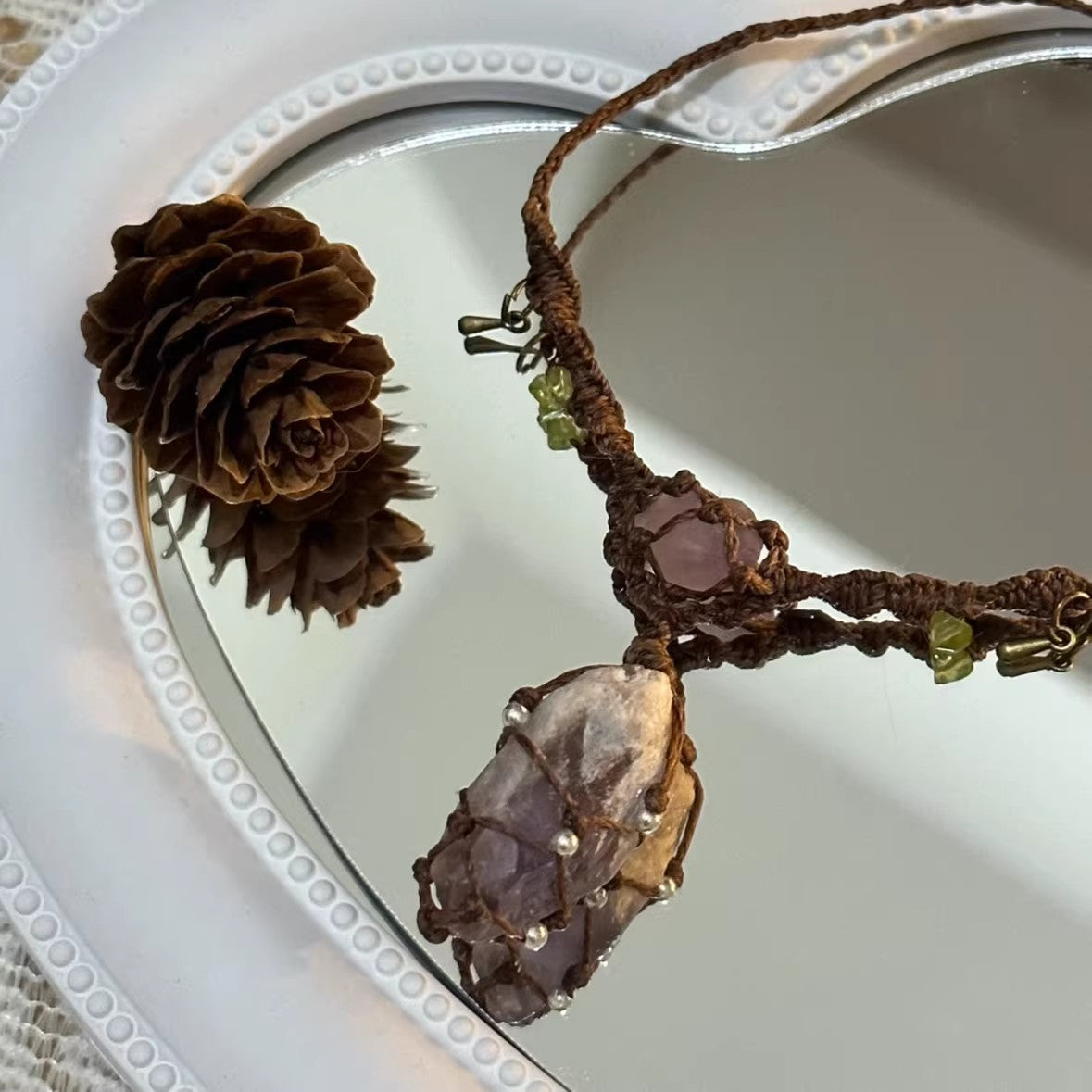 Handmade dark brown macrame amethyst crystal necklace on mirror background